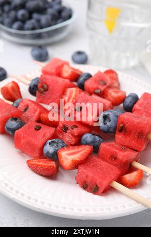 Spiedini con gustosi anguria, fragole e mirtilli sul tavolo, primo piano Foto Stock