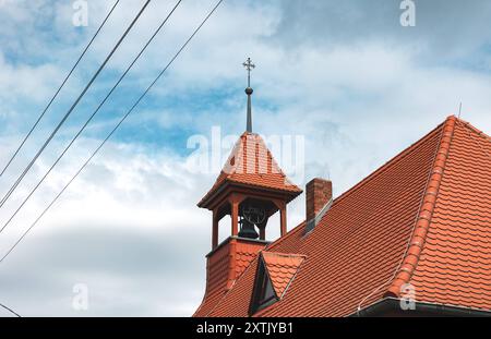 Torre della chiesa con una croce in cima e una campana in campanile. Torre della chiesa con una croce in cima e una campana nel campanile di Dessau, Sassonia-Anhalt, Germania. Cavi elettrici laterali. Religione, cristianesimo, luogo di culto, pregare, credere. Archit Church B97A7741 Foto Stock