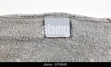 Etichetta vuota degli indumenti per la cura del bucato sullo sfondo del tessuto dell'asciugamano usurato. Foto Stock