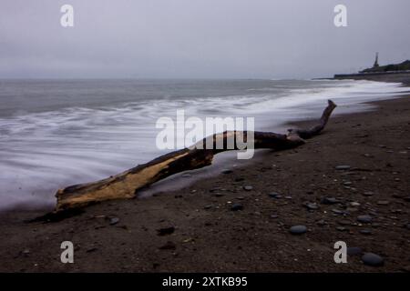 Lunga esposizione al crepuscolo con onde che si infrangono sulla spiaggia di ciottoli di Aberystwyth, in Galles Foto Stock