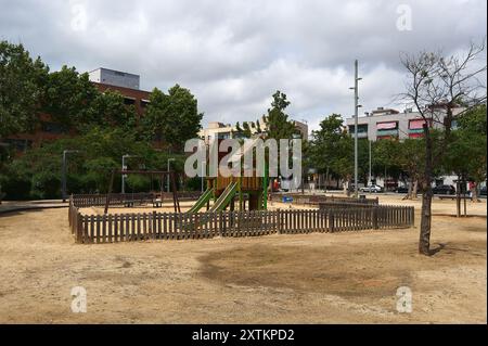 Parco per bambini con scivoli e altalene in una giornata nuvolosa, circondato da edifici residenziali. Foto Stock