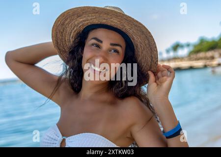 Questa tentatrice tropicale sta vivendo la sua vita migliore nella Riviera Maya. La sua posa sicura e il suo sorriso sensuale, combinati con lo splendido sfondo della spiaggia. Foto Stock