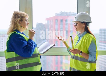 Due lavoratrici industriali che effettuano misurazioni di finestre per la decorazione Foto Stock