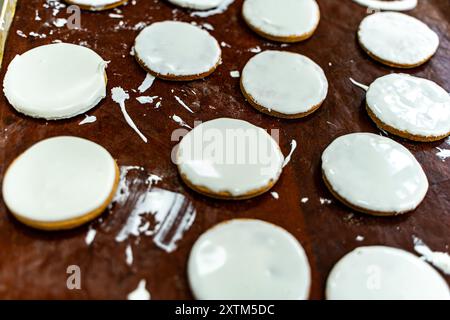 Biscotti con glassa bianca su una teglia da forno. Produzione di biscotti. Mini panificio o linea di produzione industriale per prodotti a base di farina. Foto di alta qualità Foto Stock