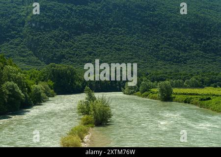 Un tortuoso fiume scorre pacificamente attraverso un lussureggiante paesaggio verde, annidato tra dolci colline ricoperte da fitte foglie. Foto Stock