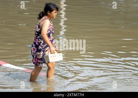 SAMUT PRAKAN, TAILANDIA, febbraio 02 2024, Una donna cammina attraverso una strada allagata Foto Stock