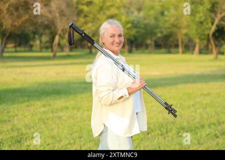 Donna matura con pali da passeggio nel parco Foto Stock