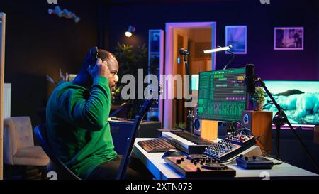 Produttore che crea un brano suonando la chitarra acustica in studio, registrando canzoni e cantando al microfono. Ingegnere del suono che mixa e padroneggia la sua melodia con apparecchiature stereo e colonne sonore. Telecamera B.. Foto Stock