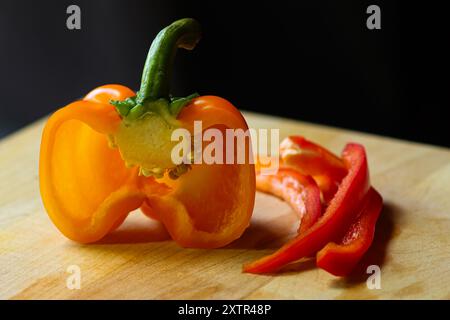 Peperoni tagliati a fette su tagliere in legno con coltello Foto Stock