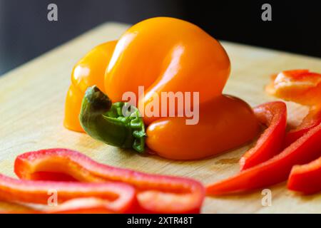 Peperoni tagliati a fette su tagliere in legno con coltello Foto Stock