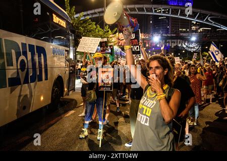 Israele. 15 agosto 2024. I manifestanti cantano mentre bloccano la strada tenendo in mano i cartelli per un accordo con gli ostaggi. Gli israeliani hanno manifestato con le famiglie degli ostaggi contro il primo ministro Benjamin Netanyahu, chiedendo un accordo immediato con gli ostaggi e il cessate il fuoco - mentre i negoziati per il cessate il fuoco a Gaza hanno luogo in Qatar. Tel Aviv, Israele. 15 agosto 2024. (Matan Golan/Sipa USA). Crediti: SIPA USA/Alamy Live News Foto Stock