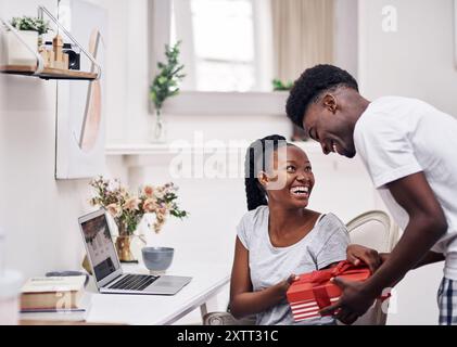 Sorridi, coppia nera e regalo d'amore a casa il giorno delle Valentine per apprezzamento, gratitudine e per celebrare il romanticismo. Uomo, donna e insieme in casa Foto Stock