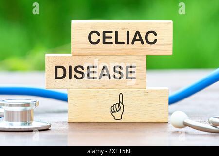 Visualizzazione concettuale della celiachia. Testo DELLA CELIACHIA su blocchi di legno sullo sfondo di piante verdi sfocate Foto Stock