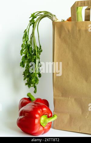 Sacchetto di carta Kraft riempito con verdure e pane freschi, su sfondo bianco, consegna di verdure fresche e shopping nei mercati locali, prodotti agricoli Foto Stock