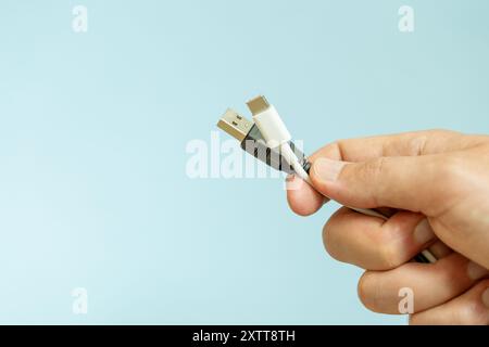 Man tiene in mano diversi cavi, diversi tipi di cavi USB, tecnologia e concetto di collegamento Foto Stock