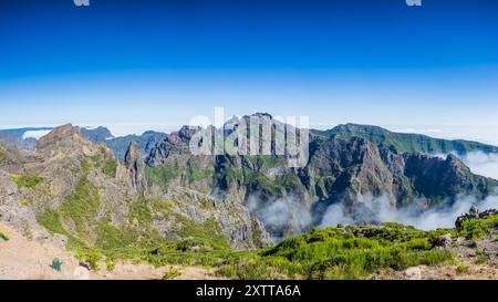 Un panorama multi-immagine di nuvole di luce che si spostano intorno a Pico do Areeiro e Pico Ruivo in alto sopra l'isola di Madeira sotto un cielo blu. Foto Stock