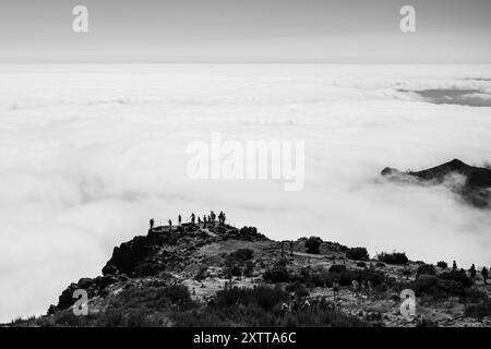 Un'immagine retroilluminata dei turisti di Pico do Areeiro si staglia contro la nuvola che circonda una delle vette più alte di Madeira. Foto Stock