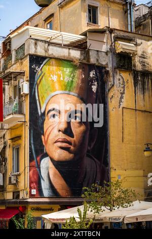 Napoli, Italia - 24 giugno 2024: Accattivante murale di un volto su un antico muro di un edificio urbano, che mette in mostra espressione artistica e vivacità culturale in un b Foto Stock