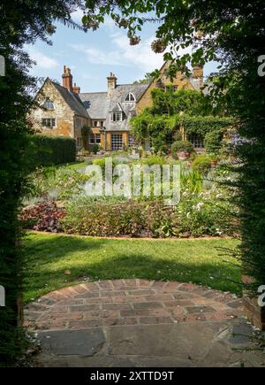 Vista della Coton Manor House and Gardens incorniciata da un arco di siepe di tasso in estate, Northamptonshire, Inghilterra, Regno Unito Foto Stock