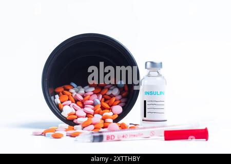 Flacone di vaccino con versamenti di pillole multicolore e siringa laterale su sfondo bianco. messa a fuoco selettiva Foto Stock