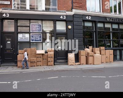 Pile di scatole di cartone fuori dai locali nel centro di Londra, con stampe piccole e grandi sull'esterno Foto Stock