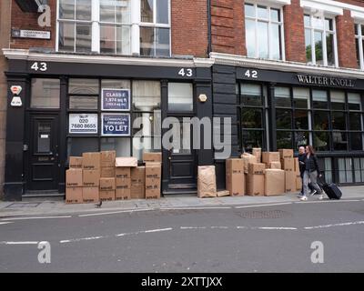 Pile di scatole di cartone fuori dai locali nel centro di Londra, con stampe piccole e grandi sull'esterno Foto Stock