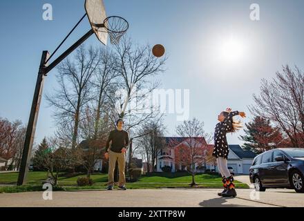 Il bambino gioioso lancia il basket in alto mentre il padre guarda Foto Stock