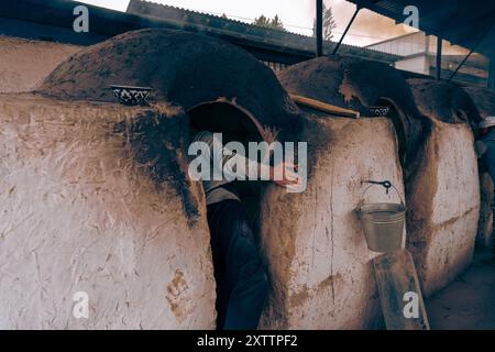 Un uomo è appoggiato su un muro di fronte ad un forno in mattoni Foto Stock