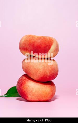 tre pesche mature su sfondo rosa. Foto Stock