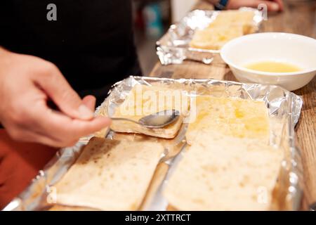 Persona che spalma il burro fuso sulle fette di pane Foto Stock