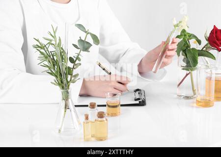 Prodotto aromaterapico. Scienziato che sviluppa oli essenziali alla tavola bianca in laboratorio, primo piano Foto Stock