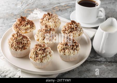 Cupcake tiramisù con glassa al mascarpone e primo piano del caffè sul piatto del tavolo. Orizzontale Foto Stock