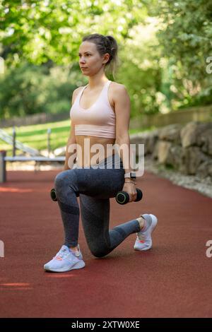 Giovane bella donna che fa esercizi su campi sportivi all'aperto Foto Stock