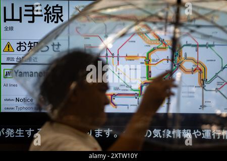 Tokyo, Giappone. 16 agosto 2024. Un pedone passa uno schermo che visualizza le informazioni sul traffico a Tokyo, Giappone, 16 agosto 2024. Ampil, il settimo tifone dell'anno, ha colpito il Giappone venerdì, forzando la cancellazione dei servizi di trasporto pubblico. Crediti: Zhang Xiaoyu/Xinhua/Alamy Live News Foto Stock