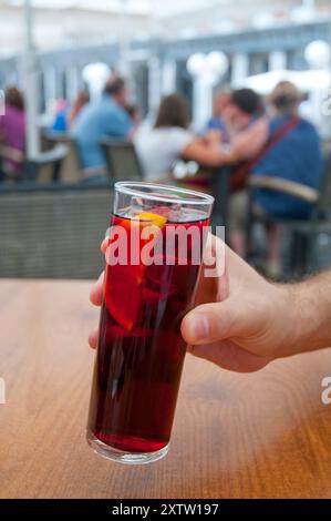 La mano di un uomo che regge un bicchiere di sangria. Piazza principale, Madrid, Spagna. Foto Stock