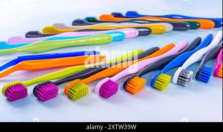 Vista dall'alto degli spazzolini da denti colorati su sfondo color pastello. Un vivace assortimento di spazzolini colorati disposti in modo ordinato in fila, ideale per il den Foto Stock