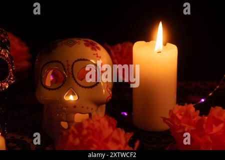 Uno spettacolo mozzafiato di Día de los Muertos con due teschi. Uno è decorato con fiori metallici, l'altro contiene una candela all'interno. Surroun Foto Stock