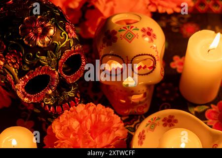 Una vista dettagliata di due teschi su sfondo nero. Uno decorato con fiori metallici e l'altro con una candela accesa all'interno. Circondato da o. Foto Stock