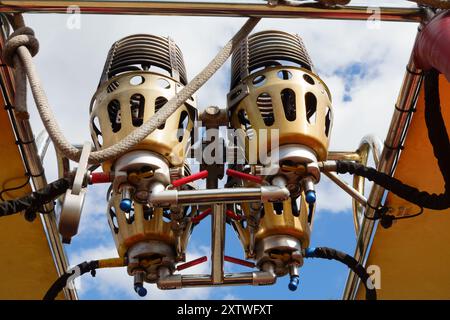 Bruciatori a gas con palloncino ad aria calda visti dal basso con un cielo blu nuvoloso. Foto Stock