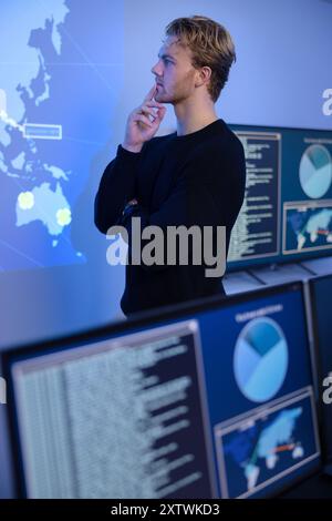 Un operatore attento e attento al Cyber Security Control Center. Più schermate che mostrano dati tecnici e avvisi. Foto Stock