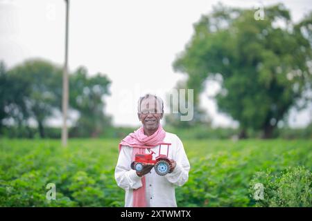 Agricoltore indiano che detiene un mini trattore giocattolo per prestito e banche , successo di poveri e vecchi agricoltori Foto Stock