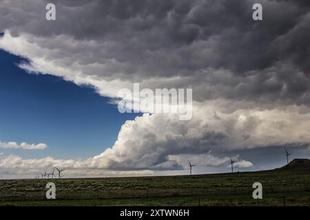 Nuvole di tempesta scure si riuniscono sopra un parco eolico su una vasta pianura aperta, annunciando una tempesta in avvicinamento. Foto Stock