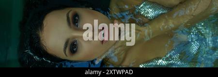 Una giovane donna con i capelli bagnati galleggia pacificamente in un acquario, i suoi occhi chiusi come se si perdesse in un sogno. Foto Stock
