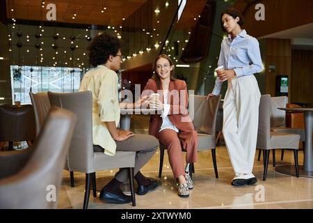 Tre diversi colleghi chiacchierano durante una pausa in un ufficio moderno. Foto Stock