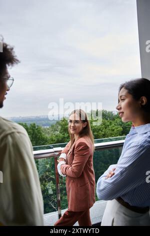 Gruppi diversi di colleghi si godono una conversazione sulla terrazza sul tetto con vista sulla città. Foto Stock
