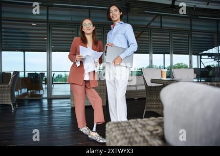 Due colleghi, uno con una gamba protesica, chiacchierano sulla terrazza sul tetto del loro moderno ufficio. Foto Stock