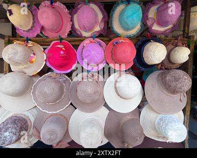 Una fila di cappelli viene visualizzata su un rack, con una varietà di colori e stili. I cappelli sono disposti in modo da facilitare la navigazione dei clienti Foto Stock