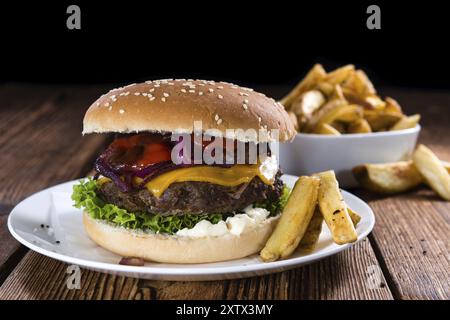 Grande fatta fresca Burger il legno rustico sfondo (con patatine fritte) Foto Stock