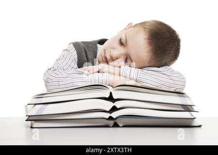 Bambino stanco che dorme sull'educazione leggendo libri alla scrivania della scuola Foto Stock