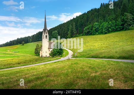 Foto mozzafiato della chiesa di Santa Maddalena di Villabassa, incastonata nelle panoramiche Dolomiti, catturandone la bellezza serena e lo sfondo maestoso. Foto Stock